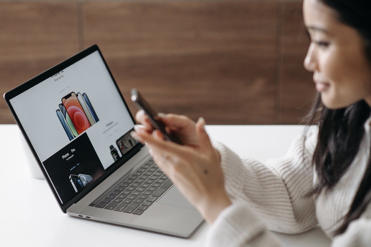 Asian woman shopping online with a laptop and smartphone at home.